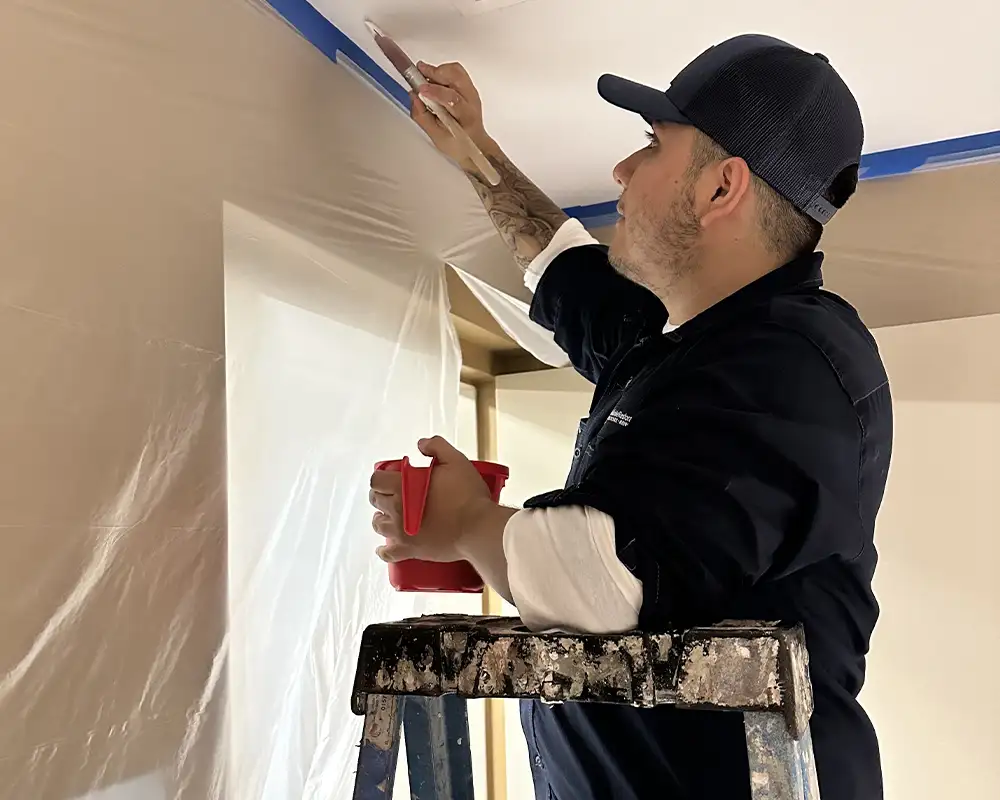 worker on a ladder painting a ceiling