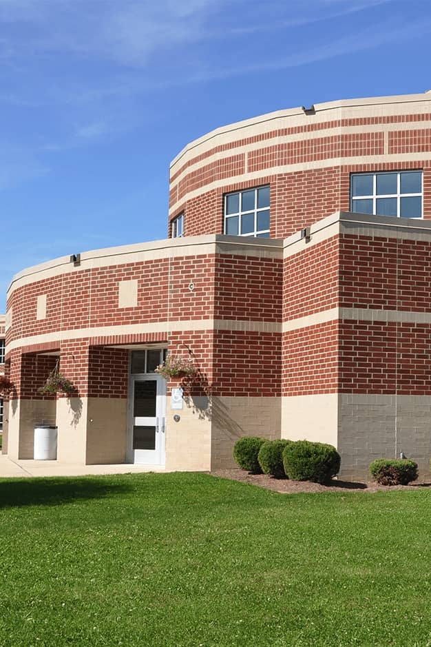 exterior of educational brick building with green lawn