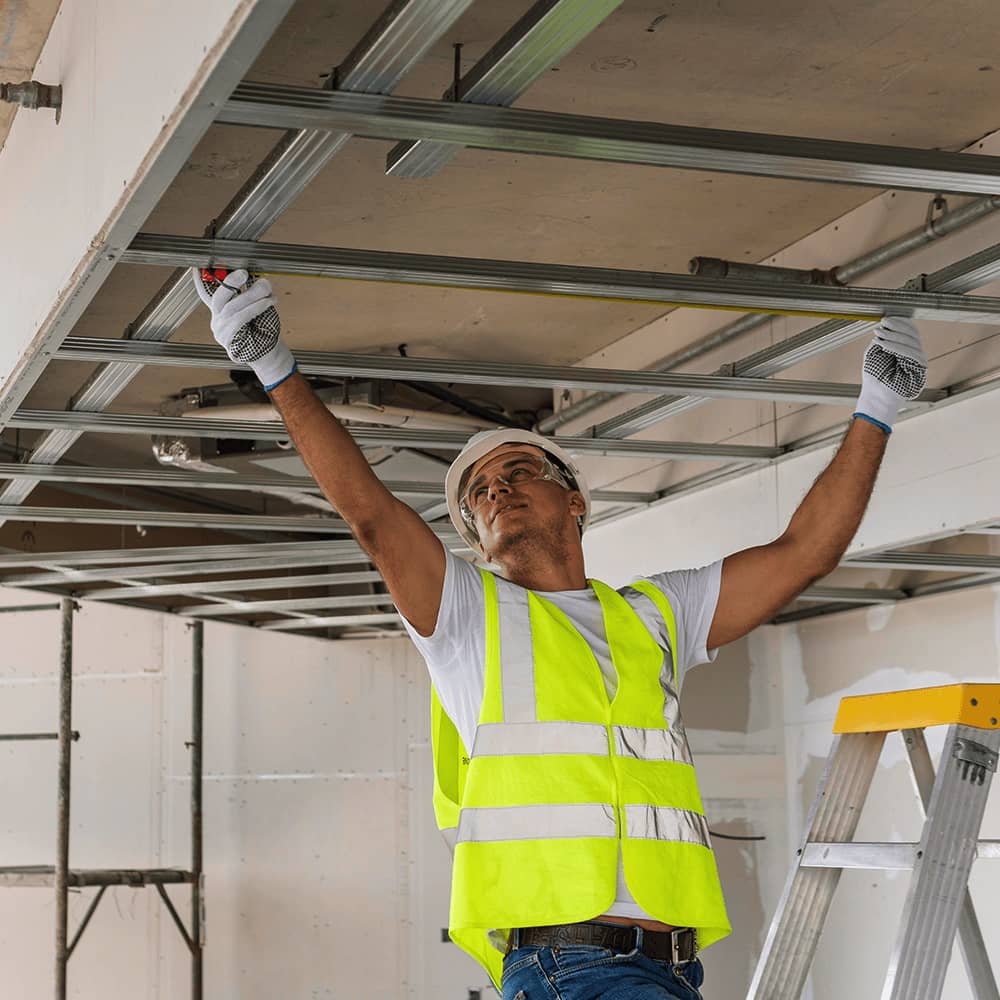 front-view-man working on a ceiling installation wearing protective gear