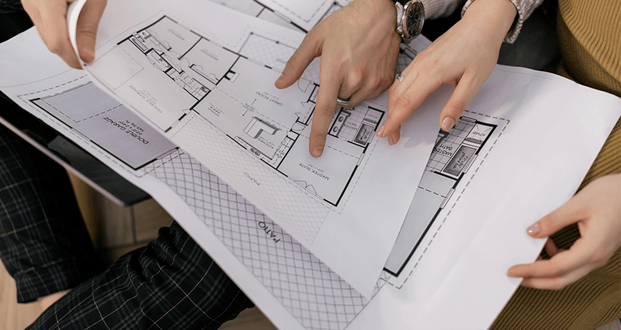 hands holding and pointing at pages of blueprints
