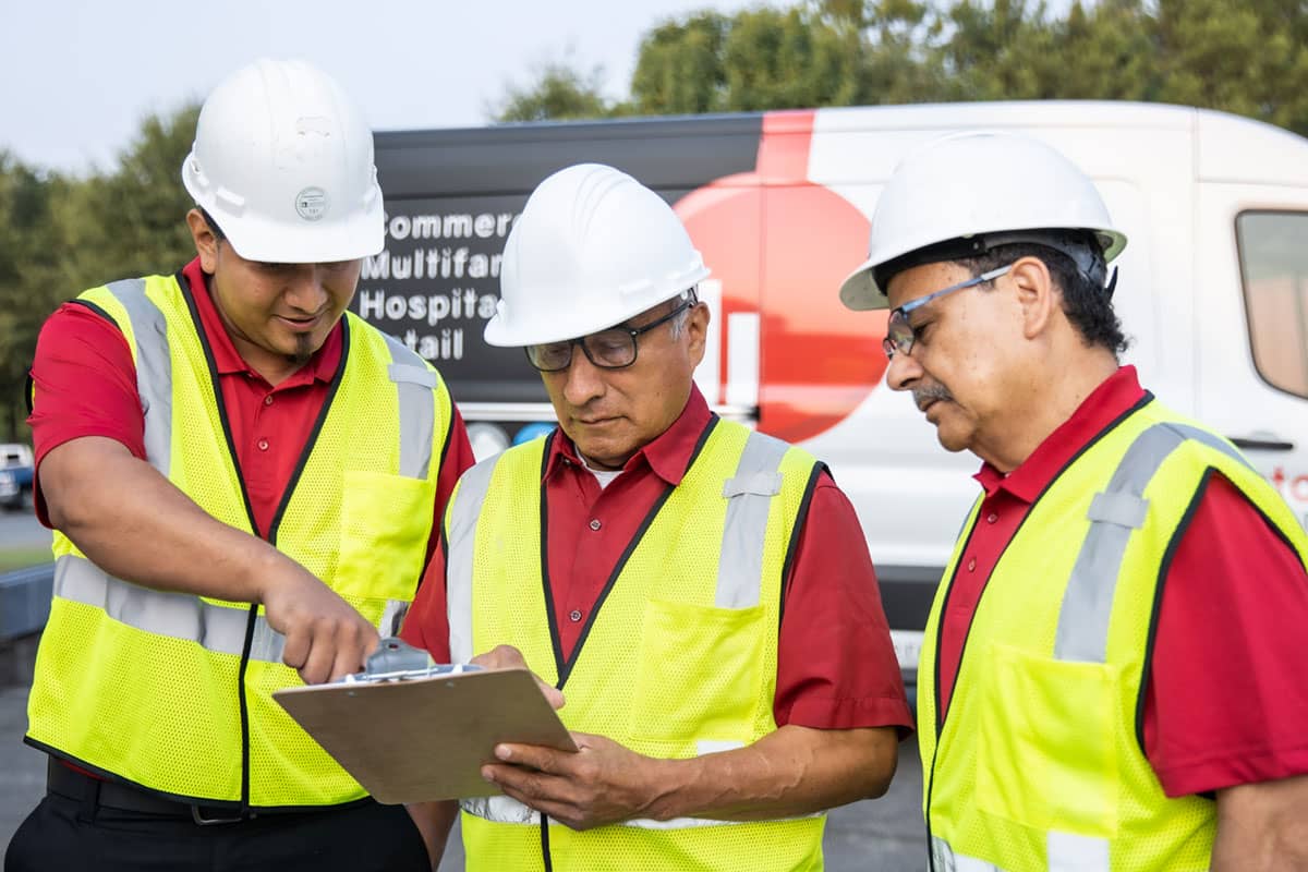 three men looking at a clipboard